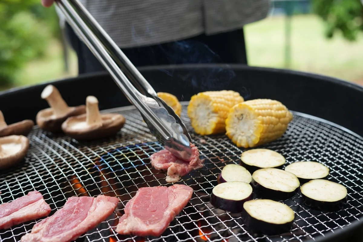 網の上で焼ける肉ととうもろこし