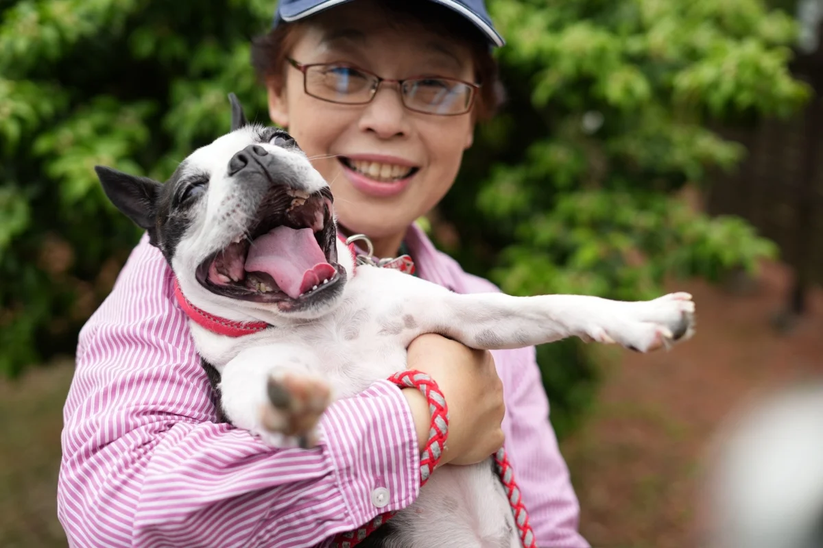A woman smiling with a dog in her arms
